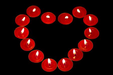 heart-shaped red burn candles on black backgroundの写真素材
