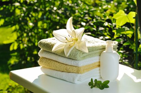 backloghting with sun white lily on stack of towels against green summer backgroundの写真素材