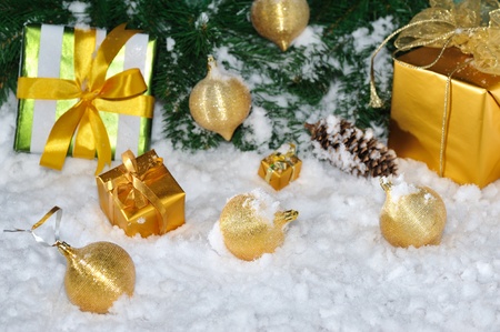 golden Christmas gift boxes and balls under decorated fir on snowの写真素材
