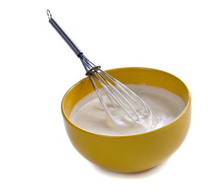 yellow bowl  with white sauce and whisk isolated on whiteの写真素材