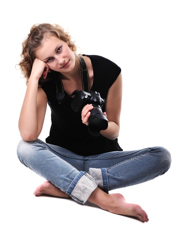 young and beautiful girl photographer with digital photocamera sitting on white backgroundの写真素材