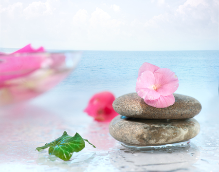 spa stone with pink flower against blue waterの写真素材