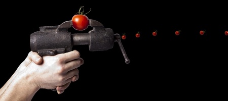 The tomato gun fire small tomato isolated on blackの写真素材
