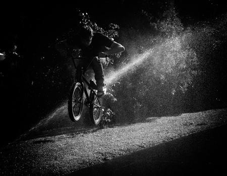 boy jumping through fountain on bmxの写真素材