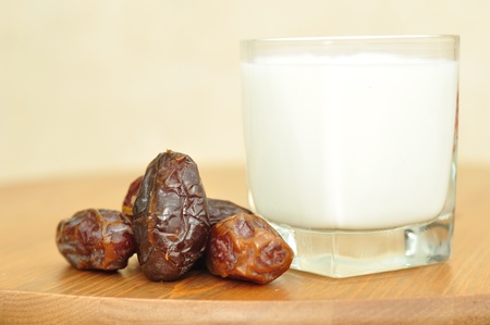 Dates and a glass of milk on a wooden table.の写真素材