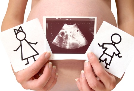   The pregnant woman holds drawings of the boy and the girl and a picture of ultrasonography of the childの写真素材