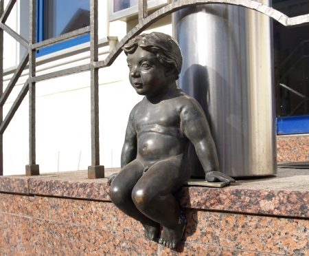 Lithuania, Klaipeda  Sculpture of the naked boy sitting on a porch of the buildingの写真素材