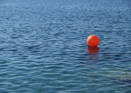 The red anchor buoy lies on a sea surfaceの写真素材