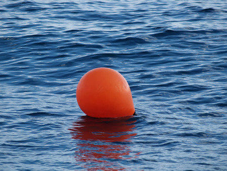 The orange buoy lies on a sea surfaceの写真素材