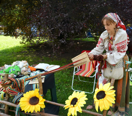 The weaver in a national suit weaves with the help reedのeditorial素材