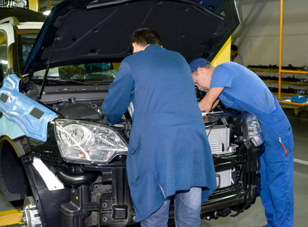 Workers mount details in podkapotny space of the car. Automobile plantのeditorial素材
