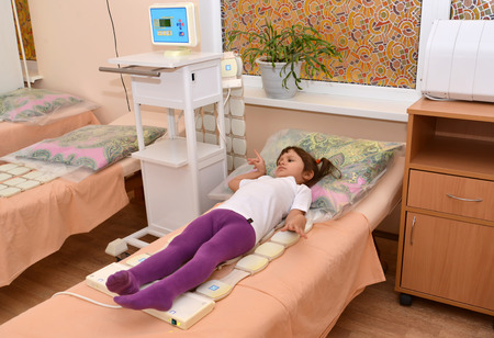 The little girl receives procedure of a magnetotherapy. Physiotherapeutic officeの写真素材