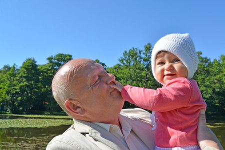The elderly man keeps on hands the little granddaughter in park