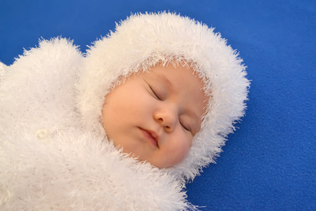 The sleeping baby in a New Year's suit of the Snowflake on a blue background, a portraitの写真素材