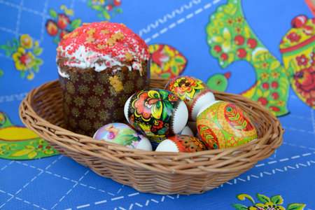Colored Easter eggs and Easter cake in a wattled support on a colorful background