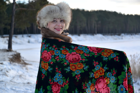 The woman in a pavlovo-posadsky scarf costs on the bank of the lake. Winter landscapeの写真素材