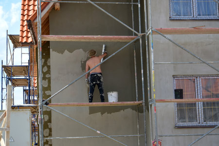 KALININGRAD REGION, RUSSIA - JUNE 01, 2016: The worker plasters a cottage facade, standing on the construction woodsのeditorial素材