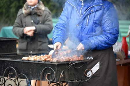 KALININGRAD, RUSSIA - NOVEMBER 13, 2016: The woman fries a shish kebab on a street brazier for saleのeditorial素材