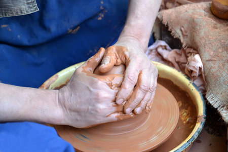 Hands of the man work with clay on a potter's wheel