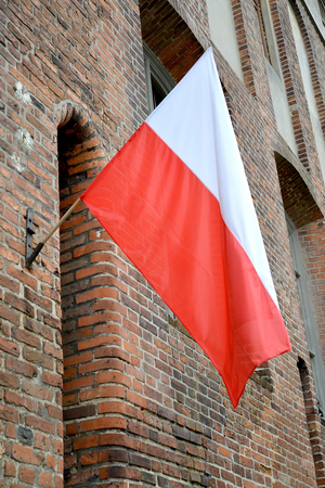 National flag of Poland is fixed on a facade of the brick buildingの写真素材