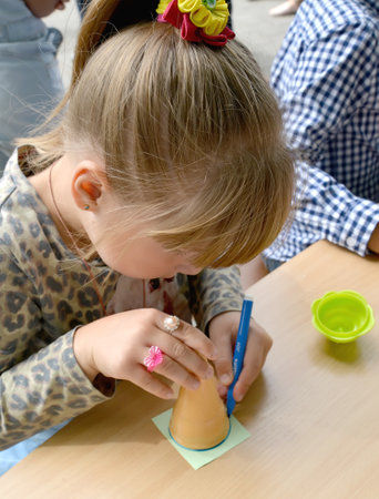 KALININGRAD, RUSSIA - JULY 08, 2018: The girl leads round a felt-tip pen a plastic cone. Children's master class in the open airのeditorial素材