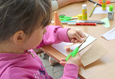 KALININGRAD, RUSSIA - JULY 08, 2018: The five-year-old girl cuts out preparation for paper applique. Children's master class in the open airのeditorial素材