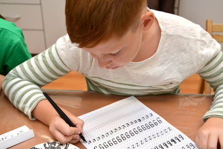 KALININGRAD, RUSSIA - JULY 05, 2019: The boy writes letters with calligraphical handwritingのeditorial素材