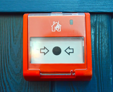 Fire alarm button on the blue wooden wall of the room