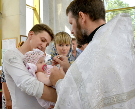 KALININGRAD, RUSSIA - AUGUST 04, 2013: Eel anointing an infant after dipping in water. Baptism riteのeditorial素材