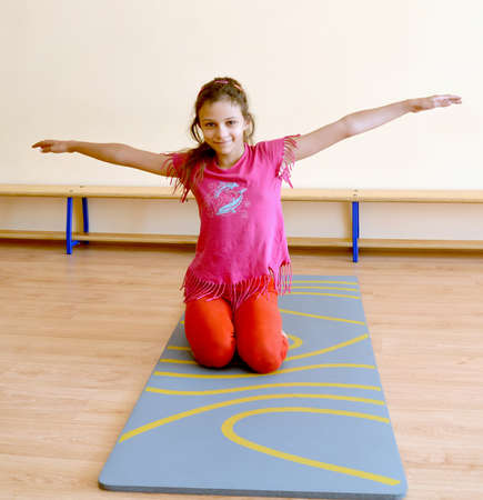 The girl performs an exercise on a gymnastics mat in the gymの写真素材