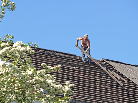 KALININGRAD, RUSSIA - MAY 24, 2007: A man stands on a roof and holds a wooden beam with his handsのeditorial素材