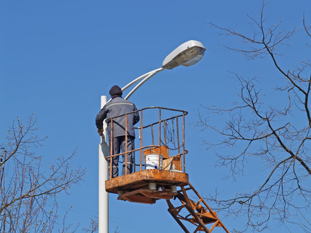 A man stands on a tower and paints a lamppostの写真素材