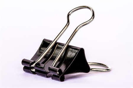 One black paper clip made of metal, isolated with a white background, for office, work, school and business conceptsの写真素材