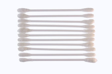 Several white cotton buds with plastic material lined up and isolated on a white background, the...