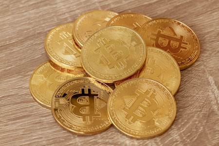 A few bitcoins on a wooden table, its value is currently increasing and growing in popularity.