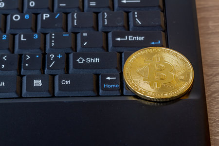 A bitcoin on a laptop keyboard, a symbol of technological developments in the exchange of goods and servicesの写真素材