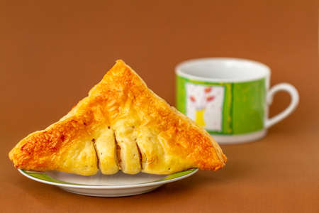 A croissant on a small plate for breakfast and coffee, brown backgroundの写真素材
