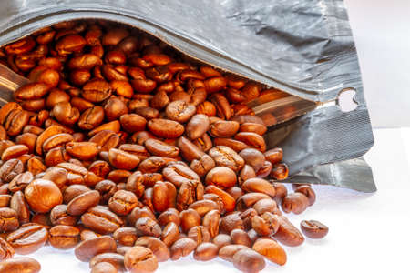 A group of coffee beans that have been roasted, poured from packaging with good circulation, ready to be grinded and made drinks, the theme of freshness and relaxの写真素材