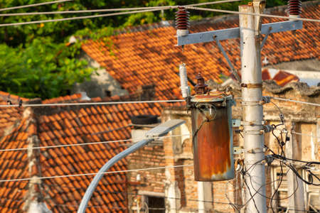 Electrical installation network with concrete poles on the streets side by side with people's houses in Indonesia, between energy needs and dangerの写真素材
