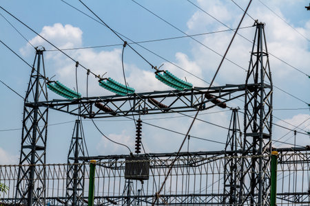 Steel structure pylons supporting high-voltage power lines for energy purposes, clear blue sky background with few cloudsの写真素材