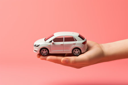 Hand holding car model isolated on pastel background with copy space, Car finance and insurance conceptの素材