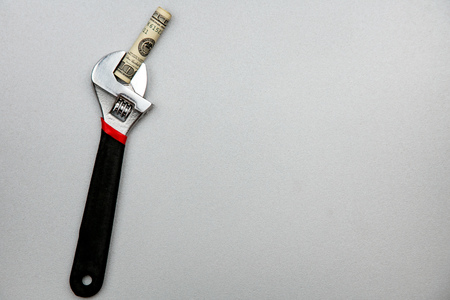 Concept of fixing currency of money and tools. Wrench and dollars on a gray background.の写真素材