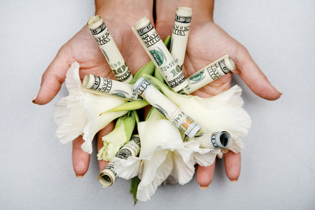 Womens hands holding money and white flowers. Set of dollars and white flowers in womens hands On Gray Backgroundの写真素材