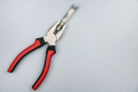 Concept of fixing currency of money and tools. Pliers and dollars on a gray backgroundの写真素材