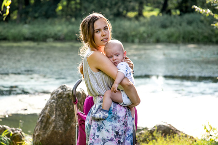 Happy mother with baby son standing in the parkの写真素材