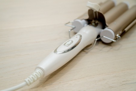 Brown hair straightener on the wooden background. Hair careの写真素材