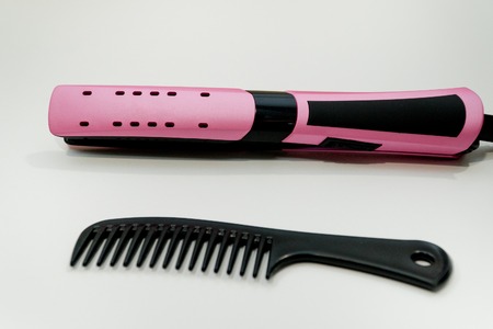 Rose hair straightener with black comb on white. Hair careの写真素材