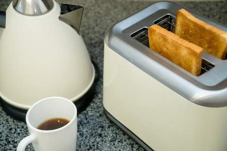 Toaster with toasted bread for breakfast, cup of coffee and kettle. Gray tableの写真素材
