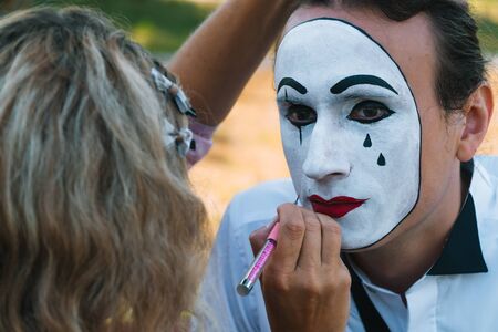 Girl paint lips to man mime with red pencilの写真素材