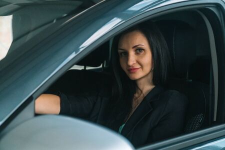 Woman wearing smart casual wear sits in car interiorの写真素材
